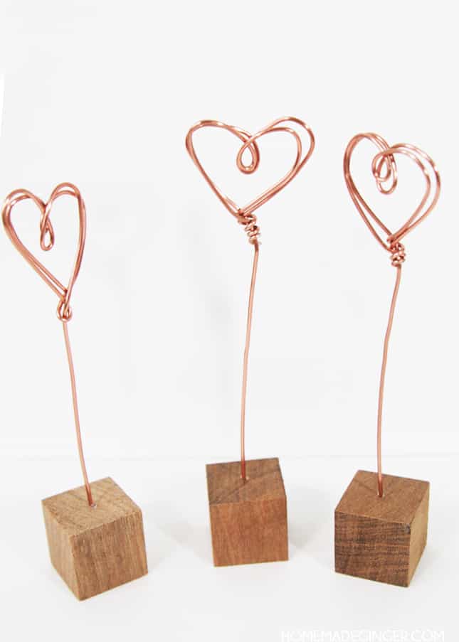 These little wire photo holders couldn't be easier to make. I saw some gold ones similar to these in different geometric shapes as I was browsing through a store a few months ago and decided to see how easy it was to make some heart versions! I also am loving all things copper right now and thought that using copper wire would send these over the edge of cuteness. I couldn't believe how easy they were to make and I LOVE how they turned out!!</p> <!-- /wp:paragraph -->  <!-- wp:paragraph --> <p><strong>It's simple to make wire photo holders at home. All you need is some copper wire, wooden blocks and a handful of other supplies to create DIY photo holders for your home.
