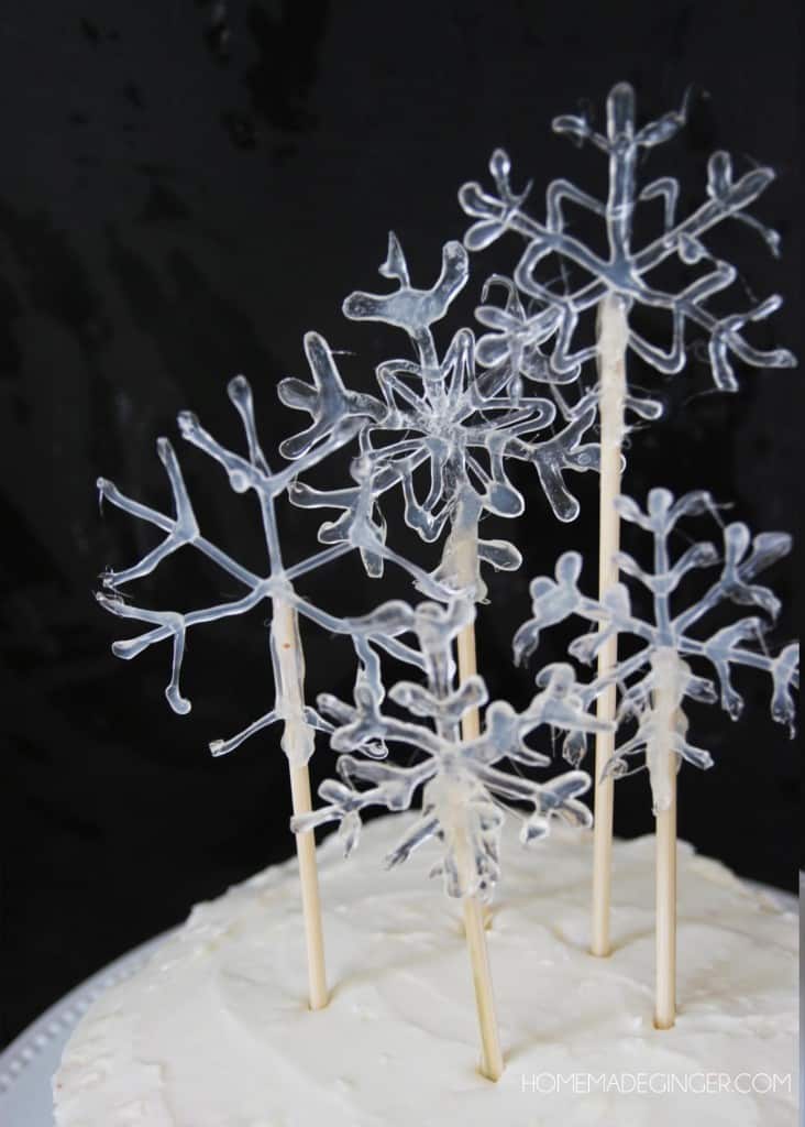 Make some snowflake cake toppers using hot glue. This will make a beautiful DIY cake decoration for any winter occasion!